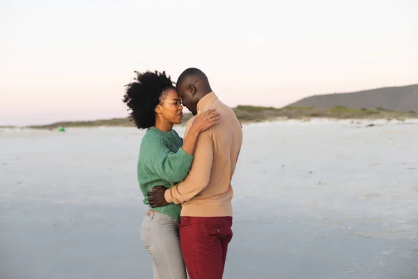 Glad Afrikansk Amerikansk Par Omfamnar Och Ler Stranden Vid Solnedgången — Stockfoto