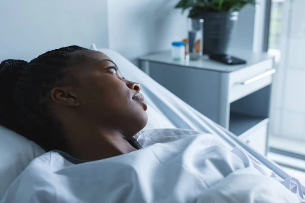 アフリカ系アメリカ人女性の患者を離れて見て 病院の部屋でベッドの上に横たわっていた 変更なし — ストック写真