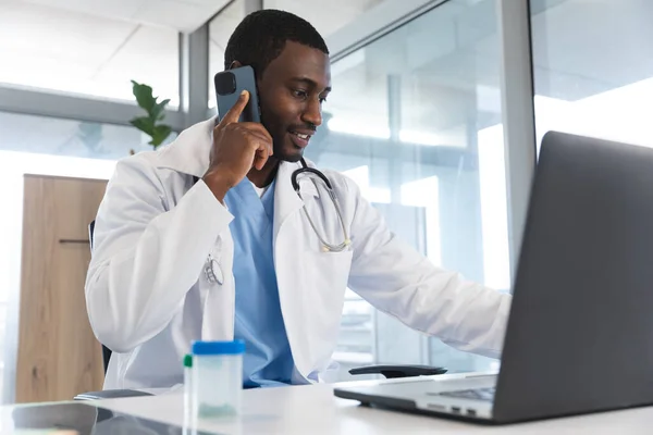Afro Amerikan Erkek Doktor Dizüstü Bilgisayar Kullanıyor Hastanede Akıllı Telefondan — Stok fotoğraf