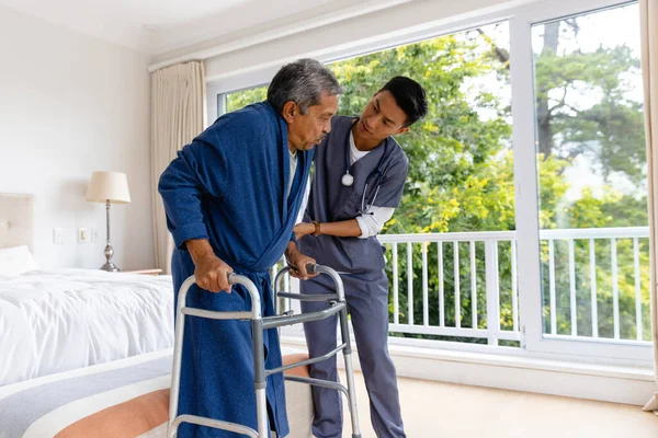 自宅で松葉杖を使う高齢男性患者を助ける多様な男性医師 医療サービス チェックアップ 家庭訪問 健康と高齢者のライフスタイル 変更なし — ストック写真