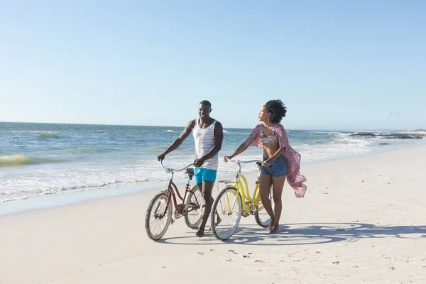 Glad Afrikansk Amerikansk Par Promenader Med Cyklar Solig Strand Till — Stockfoto