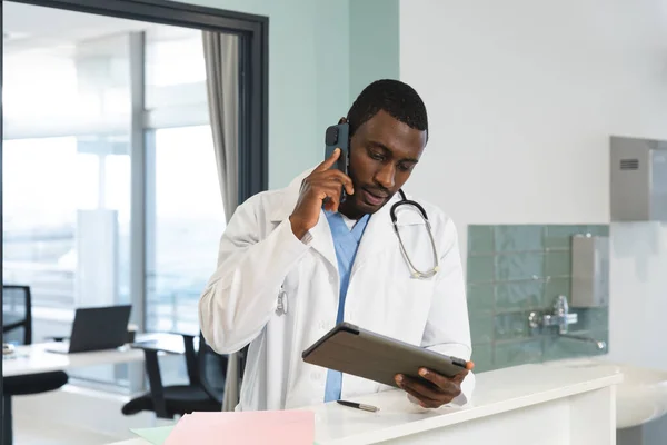 Médico Afroamericano Que Usa Tableta Habla Por Teléfono Inteligente Hospital —  Fotos de Stock