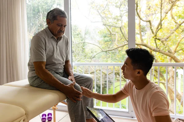 Διαφορετικός Άντρας Φυσιοθεραπευτής Που Εξετάζει Ηλικιωμένο Άνδρα Ασθενή Χρησιμοποιώντας Δισκίο — Φωτογραφία Αρχείου