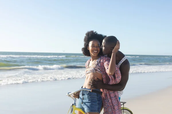 Glad Afrikansk Amerikansk Par Omfamna Ridning Cykel Solig Strand Till — Stockfoto