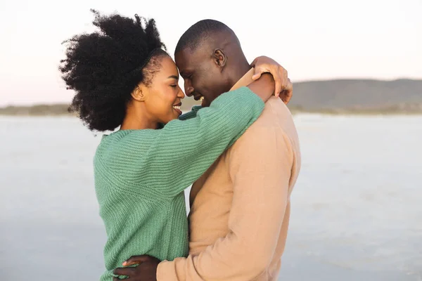 幸せなアフリカ系アメリカ人の夫婦が日没時にビーチで抱き合って笑顔 ロマンスと休暇 変更なし — ストック写真