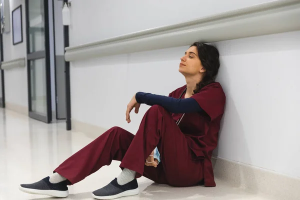 疲惫的高加索女医生穿着洗发水 坐在医院走廊的地板上 精神健康 保健和工作 — 图库照片