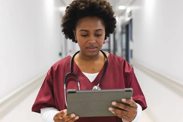 African American Female Doctor Wearing Scrubs Stethoscope Using Tablet Corridor — Stock Photo, Image