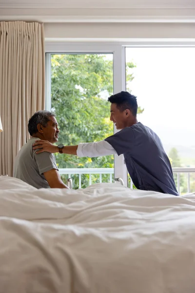 Mutlu Erkek Doktor Kıdemli Erkek Hasta Yatakta Oturup Evde Tartışıyorlar — Stok fotoğraf