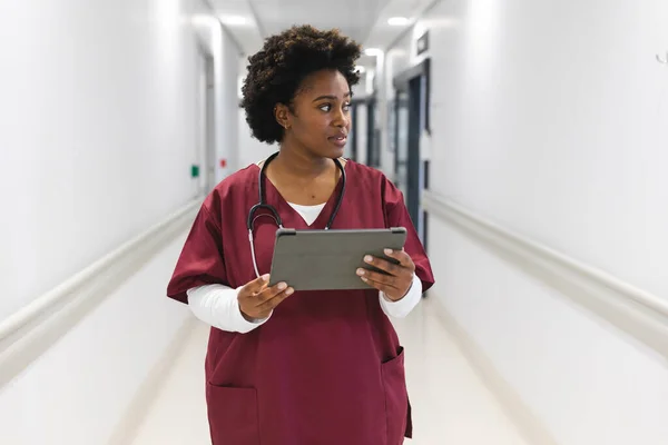 African American Female Doctor Wearing Scrubs Stethoscope Using Tablet Corridor — Stock Photo, Image