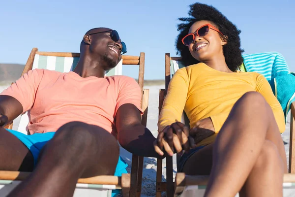 Feliz Casal Afro Americano Sentado Espreguiçadeiras Mãos Dadas Praia Ensolarada — Fotografia de Stock