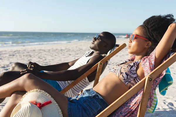 Feliz Pareja Afroamericana Gafas Sol Sentada Tumbonas Relajándose Soleada Playa —  Fotos de Stock
