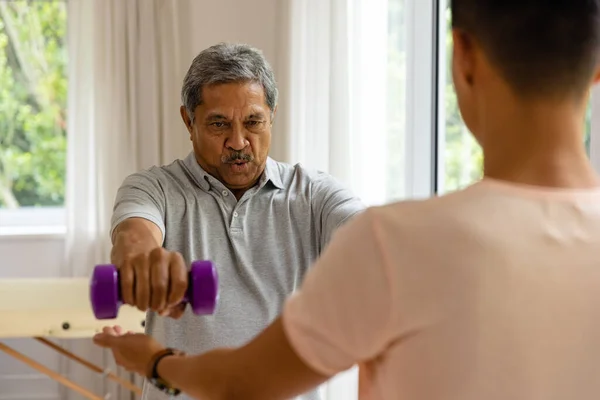 Diverse Male Physiotherapist Advising Determined Senior Male Patient Using Dumbbells — Stock Photo, Image