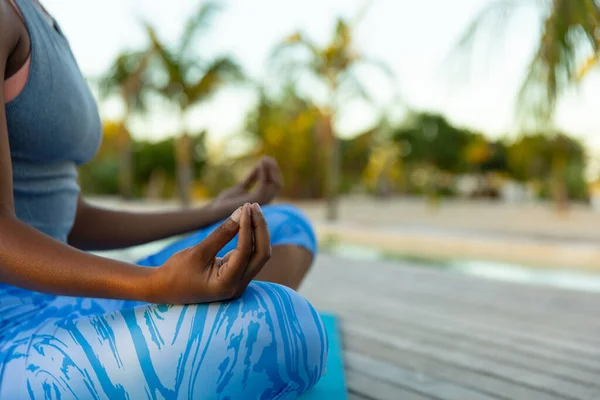非洲裔美国妇女的中段坐在阳光充足的海滩上练习瑜伽冥想 莲花的位置 健康的生活方式 夏天和假期 — 图库照片