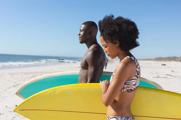 健康的非洲裔美国夫妇手持冲浪板站在海边阳光明媚的海滩上 健康的生活方式 业余爱好 冲浪和度假 — 图库照片