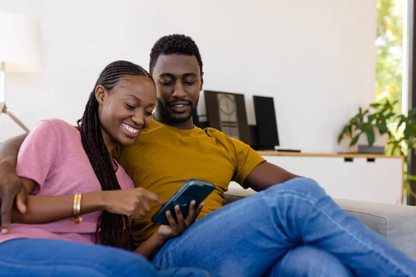 Mutlu Afro Amerikan Çifti Gülümsüyor Kucaklaşıyor Evdeki Kanepede Akıllı Telefon — Stok fotoğraf