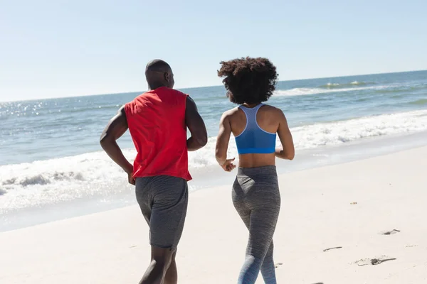 適切なアフリカ系アメリカ人のカップル運動の背面ビューは 日当たりの良いビーチで実行されます 健康的なライフスタイル フィットネス 自由な時間と休暇 変更なし — ストック写真