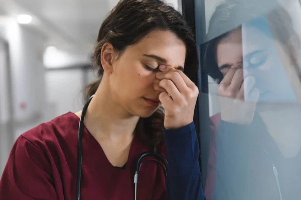疲惫的高加索女医生穿着洗发水 靠着墙躺在医院走廊里 精神健康 保健和工作 — 图库照片