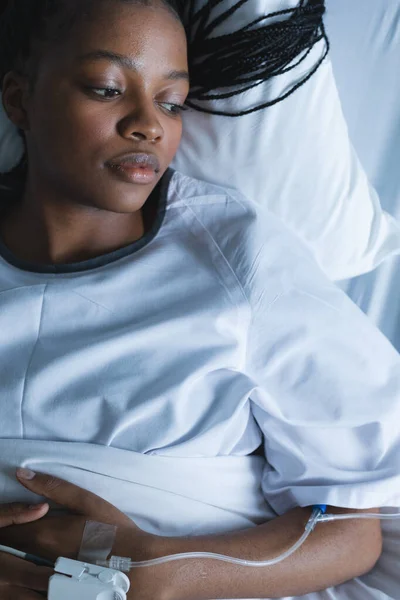アフリカ系アメリカ人女性の患者で 点滴を手に 病院の部屋のベッドの上に横たわっていた 変更なし — ストック写真