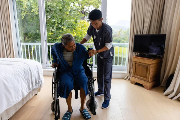 不同的男医生帮助老年男病人从轮椅上站起来 医疗服务 医疗保健 福利和老年生活方式不变 — 图库照片
