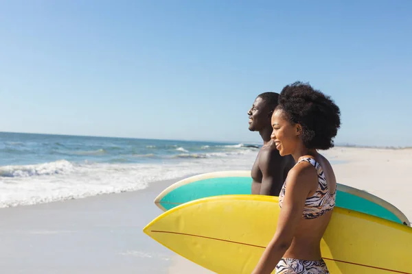 海への日当たりの良いビーチで歩いてサーフボードを運ぶアフリカ系アメリカ人のカップルに適合し スペースをコピーします 健康的なライフスタイル スポーツ サーフィンや休暇 変更なし — ストック写真