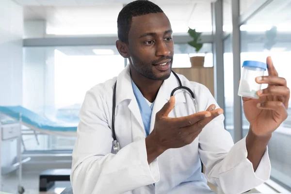 アフリカ系アメリカ人の男性医師は 研究室のコートと聴診器を着て 病院でビデオ通話をしています ビデオ通話 医療と仕事 変更なし — ストック写真