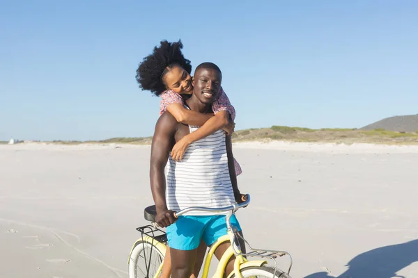 Glad Afrikansk Amerikansk Par Omfamna Ridning Cykel Solig Strand Sommar — Stockfoto
