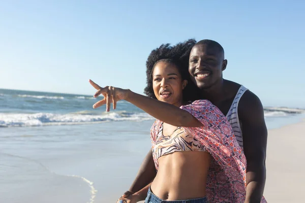 幸せなアフリカ系アメリカ人のカップルを受け入れ 海で日当たりの良いビーチを指しています ロマンス リラックス 団結と休暇 変更なし — ストック写真