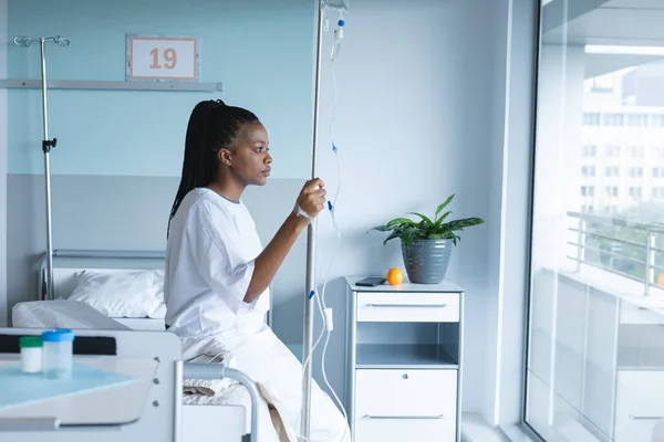 アフリカ系アメリカ人の女性患者がベッドに座り 病院の部屋の窓を見透かしている 変更なし — ストック写真