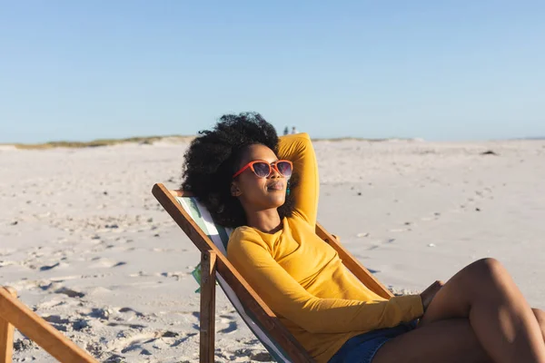 Güneş Gözlüklü Mutlu Afro Amerikalı Kadın Güneşli Sahilde Şezlongda Dinleniyor — Stok fotoğraf