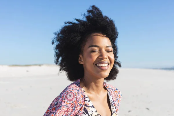 快乐的非洲裔美国女人坐在阳光灿烂的海滩上 闭着眼睛 面带微笑 放松和假期 — 图库照片