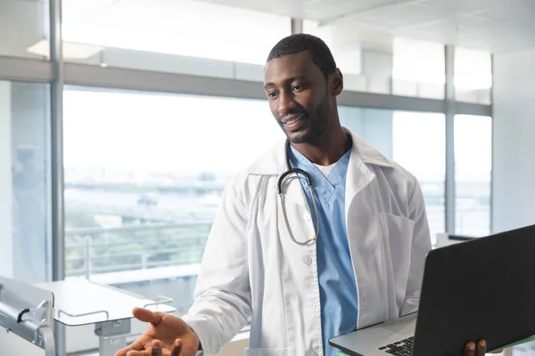 アフリカ系アメリカ人の男性医師は 病院のラップトップを使用して ラボコートと聴診器を身に着けています コミュニケーション 医療と仕事 変更なし — ストック写真