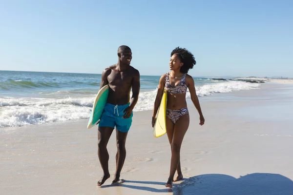 Boldog Egészséges Afro Amerikai Házaspár Szörfdeszkákat Cipelve Sétálnak Napos Tengerparton — Stock Fotó