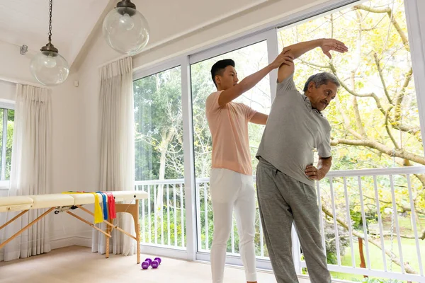 快乐多样的男性理疗师建议和老年男性患者伸展手臂 物理疗法 医疗保健 福利和老年生活方式 — 图库照片