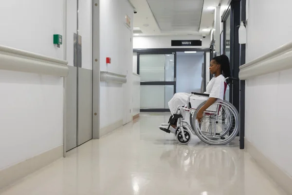Hastane Önlüğü Giymiş Koridorda Tekerlekli Sandalyede Oturan Afrikalı Amerikalı Kadın — Stok fotoğraf