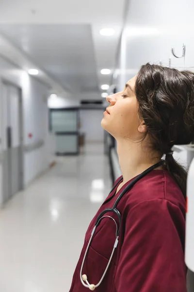 疲惫的高加索女医生穿着洗发水 靠着墙躺在医院走廊里 精神健康 保健和工作 — 图库照片
