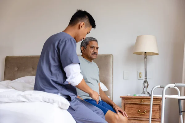 多様な男性医師と高齢男性患者がベッドに座り 自宅で議論します 医療サービス チェックアップ 家庭訪問 健康と高齢者のライフスタイル 変更なし — ストック写真