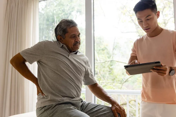 不同的男性理疗师使用平板检查老年男性患者 物理疗法 交流和老年生活方式 — 图库照片