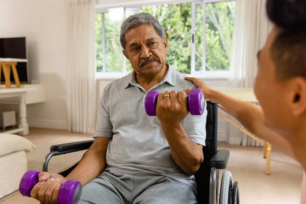 さまざまな男性理学療法士のアドバイスやダンベルを使用して車椅子の高齢男性患者 理学療法 高齢者のライフスタイル 変更なし — ストック写真