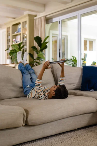 Happy Biracial Boy Lying Couch Feet Using Tablet Living Room — Stock Photo, Image