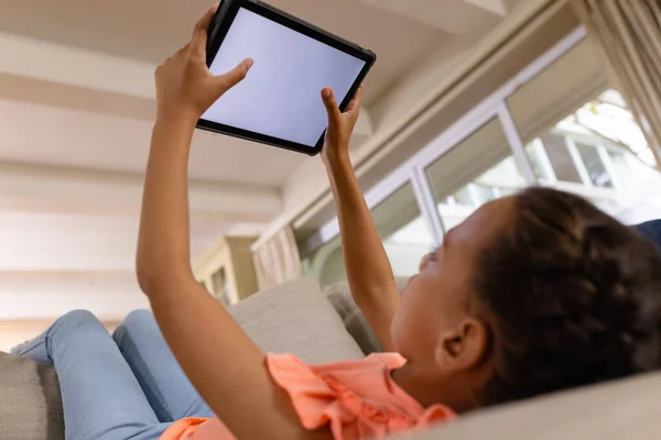 Menina Biracial Feliz Deitado Sofá Usando Tablet Com Espaço Cópia — Fotografia de Stock