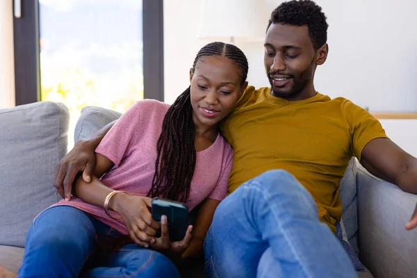 Šťastný Africký Americký Pár Usmívá Objímají Používají Smartphone Gauči Doma — Stock fotografie