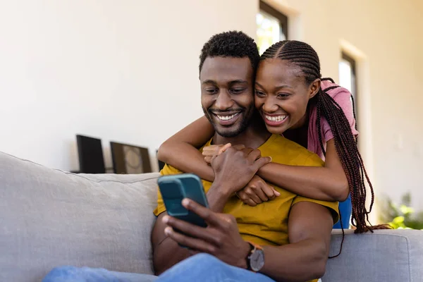 快乐的非洲裔美国夫妇在客厅里拥抱和使用智能手机 生活方式 交流和家庭生活 — 图库照片