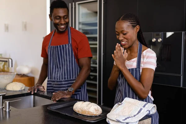 快乐的非洲裔美国夫妇 穿着围裙 在厨房里享用烤面包 生活方式 结合和家庭生活 — 图库照片