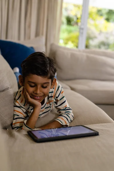 Happy Biracial Αγόρι Που Βρίσκεται Στον Καναπέ Χρησιμοποιώντας Tablet Στο — Φωτογραφία Αρχείου