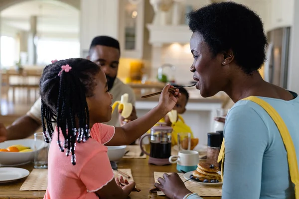 非洲裔美国女孩在饭桌上同家人一起吃早餐的时候给妈妈吃煎饼 不变的生活方式 早晨和家庭观念 — 图库照片