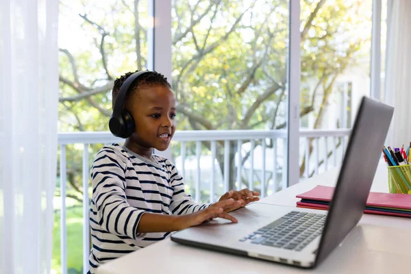 非洲裔美国人面带微笑 戴着耳机 在家里通过笔记本电脑参加网上课程 电子学习和家庭观念 — 图库照片