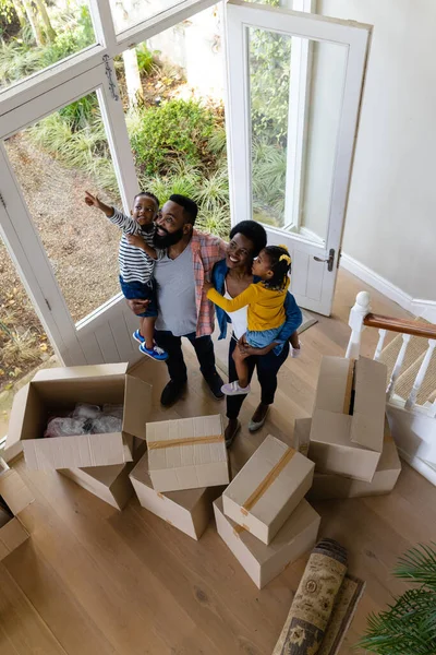 新しい家の箱のそばに立っている間に子供を運ぶアフリカ系アメリカ人の両親の高い角度のビュー 変更されていない 子供時代 移動する家と移転の概念 — ストック写真