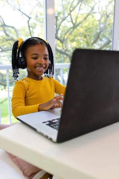 坐在家里 用笔记本电脑在线学习的非洲裔美国女孩笑着 电子学习和家庭观念 — 图库照片