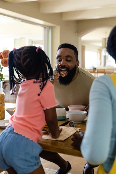 非洲裔美国人女儿在饭桌边吃早餐时给父亲吃煎饼 不变的生活方式 早晨和家庭观念 — 图库照片