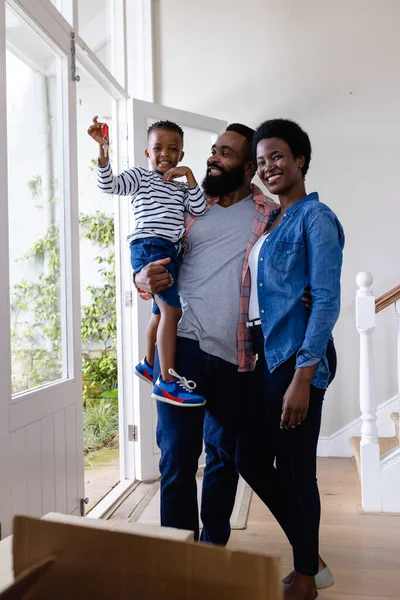 新しい家に立っている間 かわいい息子の鍵を持っている幸せなアフリカ系アメリカ人の両親 変更されていない 子供時代 引っ越しの家と移転の概念 — ストック写真